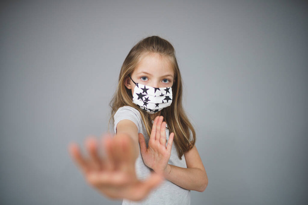 beautiful young girl with self-made protective medical mask showing stop gesture - Foto, Imagem