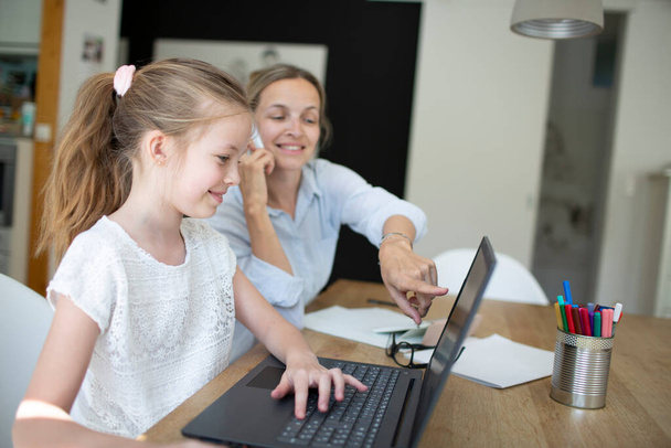 woman working from home office with her daughter homeschooling during corona crisis - Foto, Bild