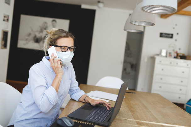 beautiful woman with medical mask working with laptop at home office - Foto, Imagem