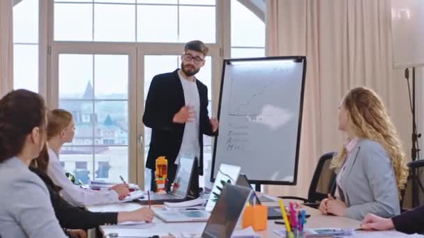 Modern office the team leader young businessman explain to his colleagues his leadership ideas and he make a training presentation - Záběry, video