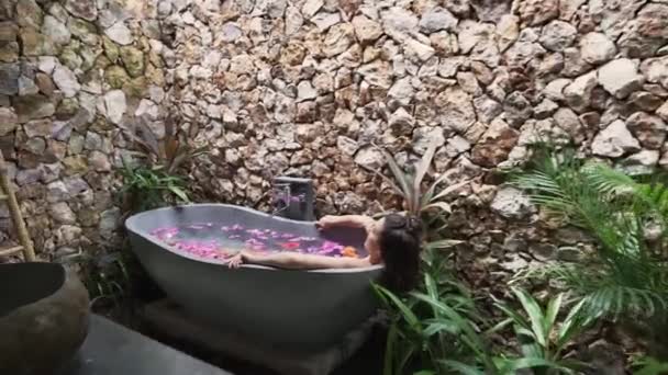 Mooie sexy dame die geniet van thuis blijven, het nemen van bloem bad in Bali. Vrouw die geestelijke gezondheid en zelfliefde ondersteunt. Concept: Spa, Behandeling, Welzijn, 4k - Video