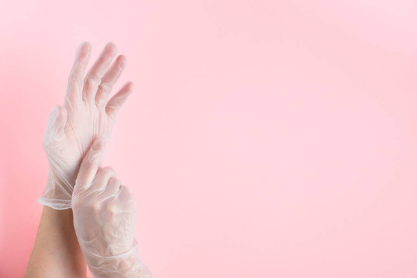 coronavirus Covid-19 pandemic. female hands wear medical gloves on pink background, protective medical tool. copy space. - Φωτογραφία, εικόνα