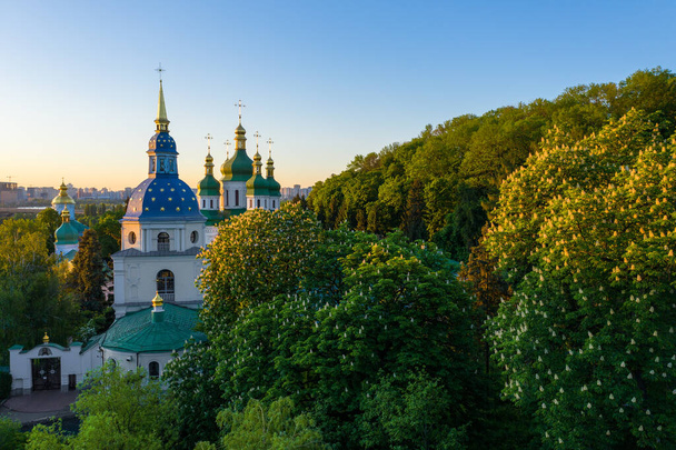 Kultaiset ja vihreät ortodoksisen kirkon kupolit keskellä syyspuistoa. Kuuluisa rakennus on hämärtynyt
. - Valokuva, kuva
