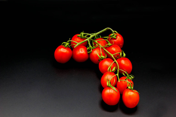 красные помидоры черри с зеленым стеблем лежат на черном фоне вид сверху, место для текста
 - Фото, изображение