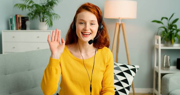Portrait of beautiful cheerful redhead girl with headsets have video call. - Foto, imagen