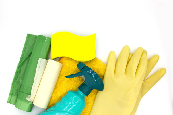 Cleaning products like a sponge, dishwasher tablet, gloves, spray bottle, garbage bag and a rag on white background with copyspace close up top view. concept clean house and hand care - Photo, Image