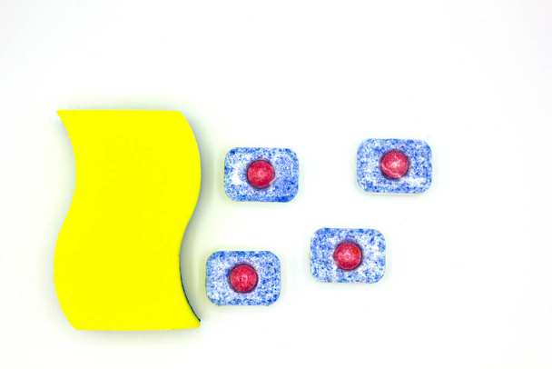 mosogatószerek: szivacs és mosogatógép tabletta felhőként és eső fehér alapon. Közelről, felülnézetből. tiszta ház, kézápolás koncepció - Fotó, kép