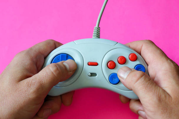 controller vintage per una console di gioco nelle mani di un uomo su sfondo rosa
 - Foto, immagini