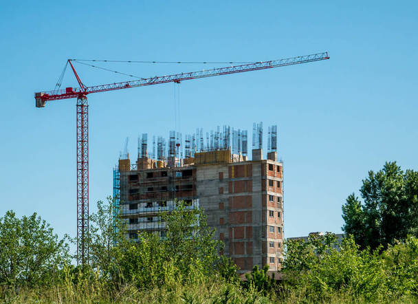 Rakentaminen nosturi ja keskeneräinen asunto tai toimistorakennus vastaan sininen taivas. Rakennuksen rakennustyömaa
 - Valokuva, kuva