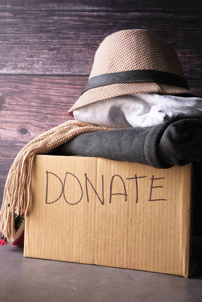 Коробка пожертвувань з пожертвувальним одягом на дерев'яному столі
 . - Фото, зображення