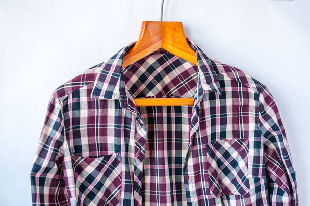 A checkered shirt hangs on a hanger - Фото, зображення