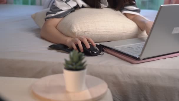 Asijská mladá žena používající notebook, ležící doma na posteli, hobby, technologie a volný čas, domácí karanténa životní styl během pandemie covid-19, práce na dálku doma, WHF koncept, práce doma - Záběry, video
