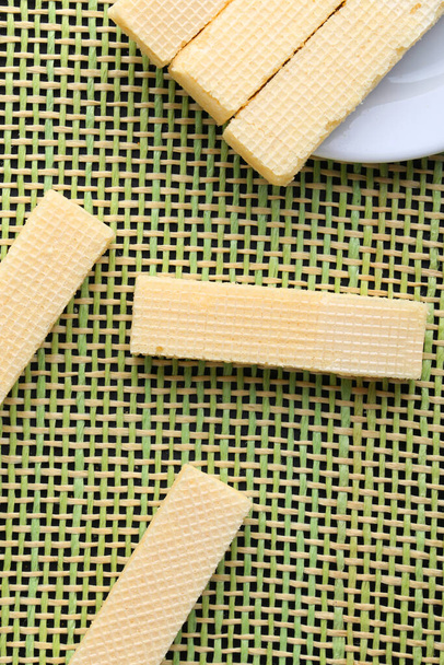Вкусные вафельные палочки на желтом фоне, плоский уголок. Сладкая еда
 - Фото, изображение