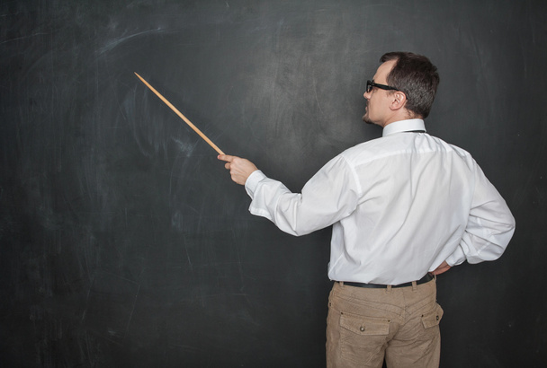 Teacher man retro style with pointer standing back to blackboard on chalkboard background - Photo, Image