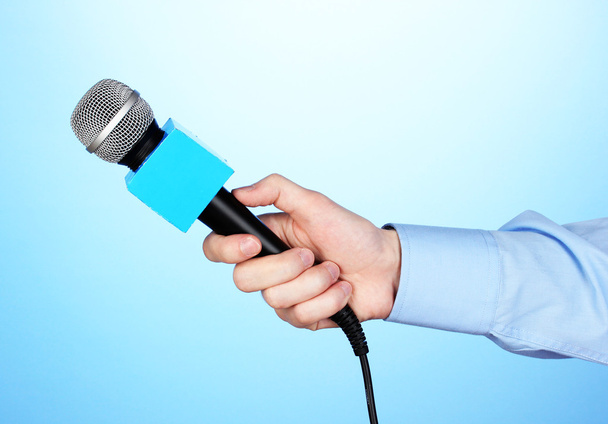 Male hand with microphone on blue background - Φωτογραφία, εικόνα