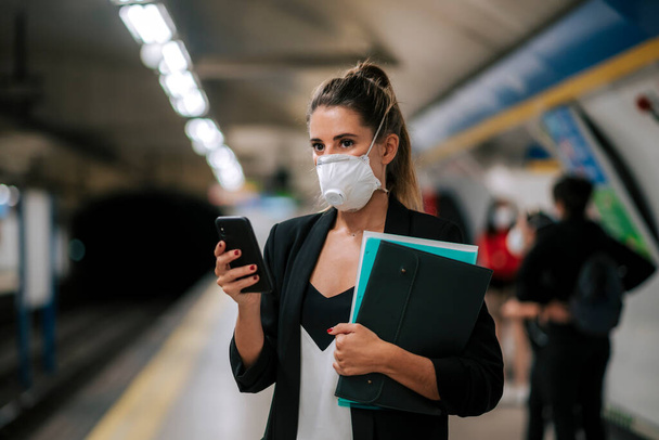 young woman with medical mask in the subway uses her phone - Foto, Bild