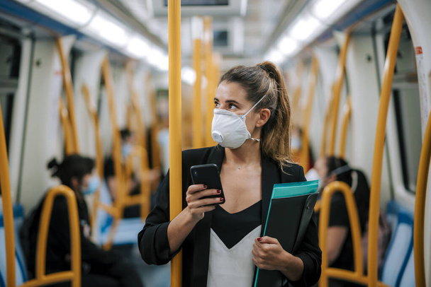 jeune femme avec masque médical dans le métro utilise son téléphone
 - Photo, image