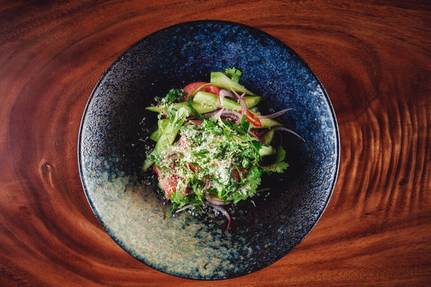 Зелений салат подається в темній мисці з дерев'яним фоном
 - Фото, зображення