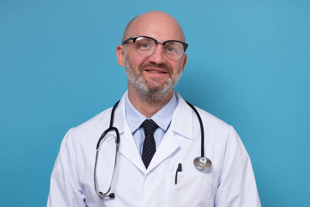 Sorridente medico maturo in cappotto bianco e stetoscopio
 - Foto, immagini