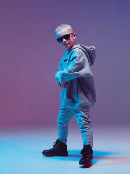Cool boy child dancing hip hop in a hoodie and glasses, in a Studio on a neon background. - Fotoğraf, Görsel