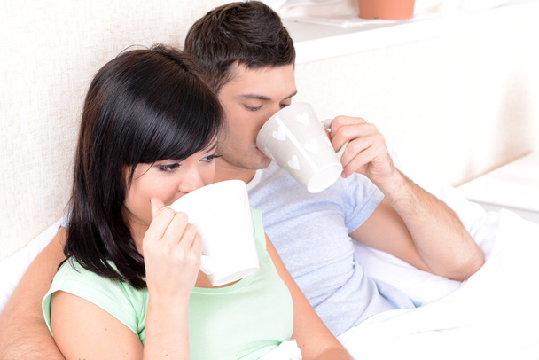 Couple in love drinking coffee in bed - Фото, зображення