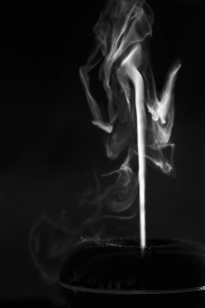 Abstrakte Figuren aus weißem fließenden Dampf aus einem Diffusor auf schwarzem Hintergrund. - Foto, Bild