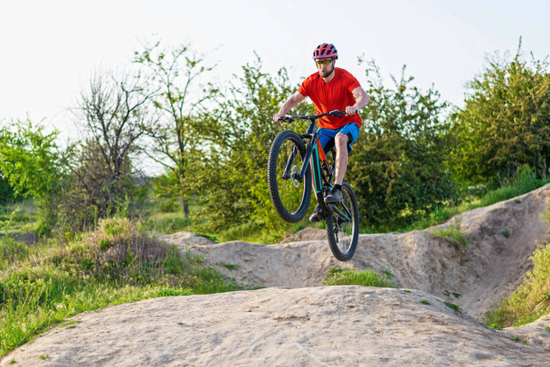 Extrémní cyklistický koncept, cyklista skákající na horském kole. Cyklista v jasně oranžovém tričku a helmě. - Fotografie, Obrázek