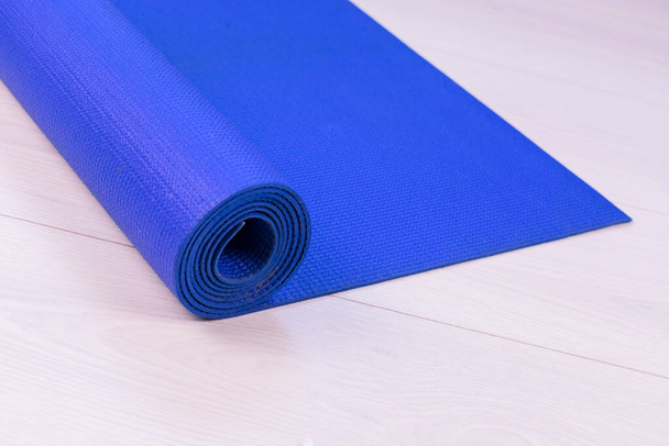 Tapis de yoga bleu sur plancher blanc en bois
. - Photo, image