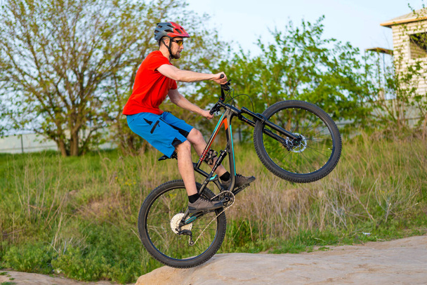 Professionele fietser in een helder T-shirt doet een sprong. Extreme sport. Fietser op een mountainbike. - Foto, afbeelding
