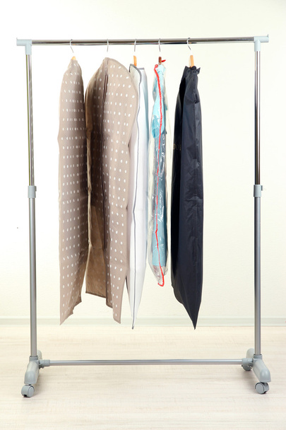 Clothes in cases for storing on hangers, on gray background - Foto, imagen