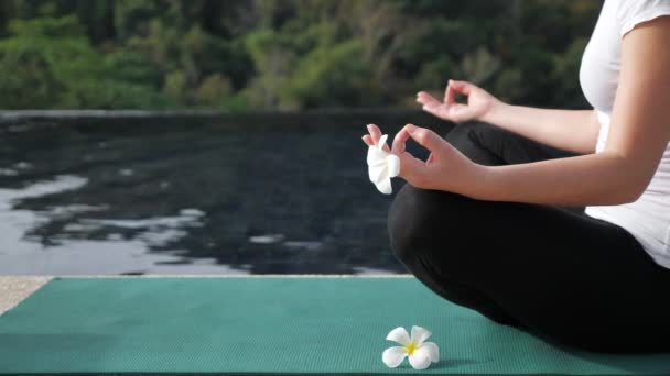 jeune femme est assise dans une position de lotus près de la piscine sur le toit. Sans visage
 - Séquence, vidéo