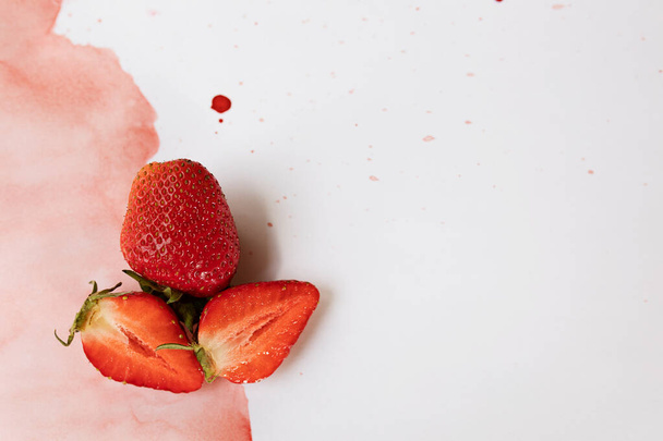 The creative composition is made of bright strawberries on a two-color watercolor background. Flat lay. The concept of food. Copy space. - 写真・画像