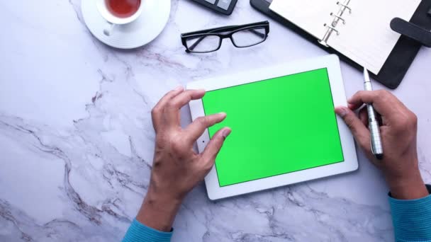νεαρός άνδρας που εργάζεται σε ψηφιακό tablet με πράσινη οθόνη  - Πλάνα, βίντεο