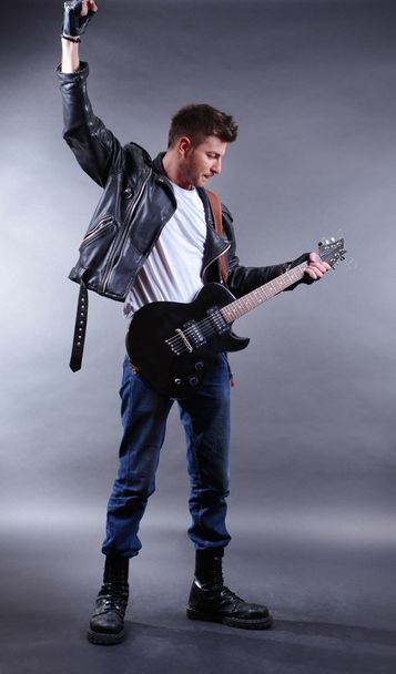 Young musician playing guitar on gray background - Foto, Bild