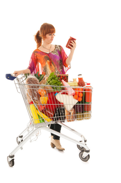 Woman with Shopping cart reading label - Φωτογραφία, εικόνα