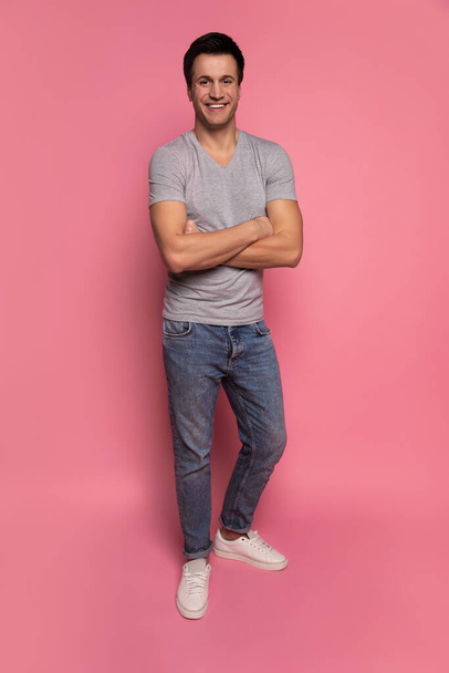 Tall and attractive. Full-length photo of a tall handsome man in casual clothes, who is standing with folded arms and looking in the camera. - Foto, imagen