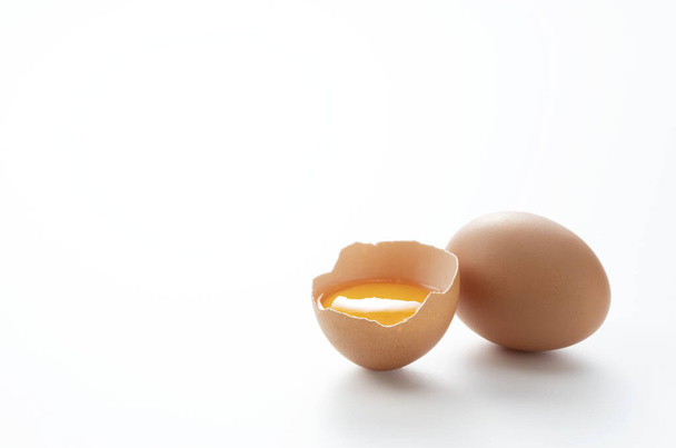 Un huevo roto colocado sobre un fondo blanco con espacio de copia fue fotografiado desde un ángulo
. - Foto, Imagen