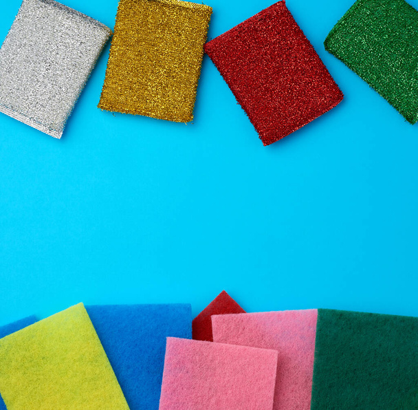 new multi-colored kitchen sponges for washing dishes on a blue background, flat lay, copy space - Fotó, kép