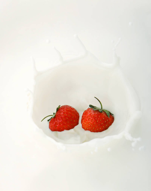 Two strawberries splashing into milk - Foto, Imagem