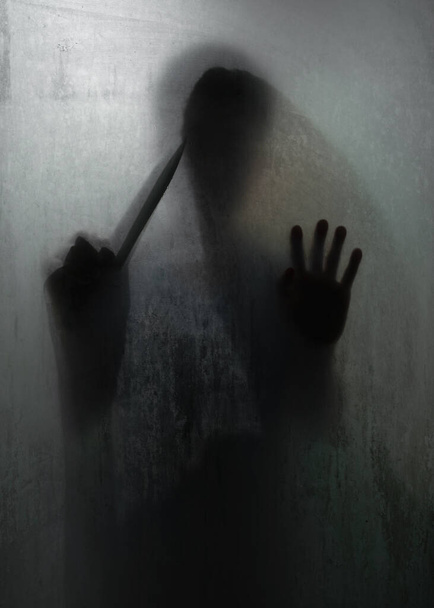 Shadow of horror murderer holding sharp knife behind frosted glass in the bathroom - Photo, Image