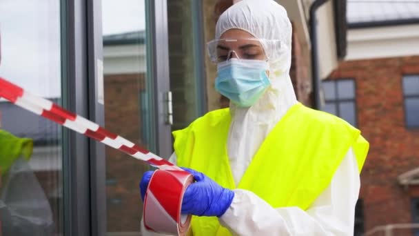 healthcare worker sealing door with caution tape - Video, Çekim