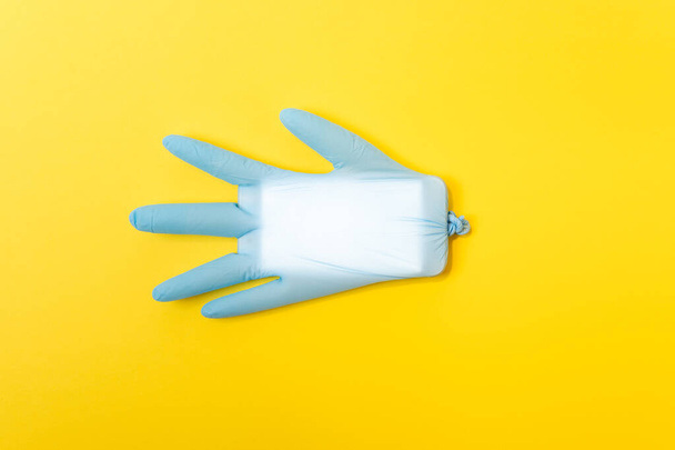 Blue latex medical glove with mobile phone inside. Minimal Coronavirus outbreak. Pandemic concept. - Valokuva, kuva
