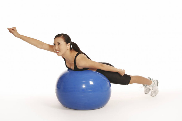 Young woman lying forward on fitness ball - Foto, Imagen