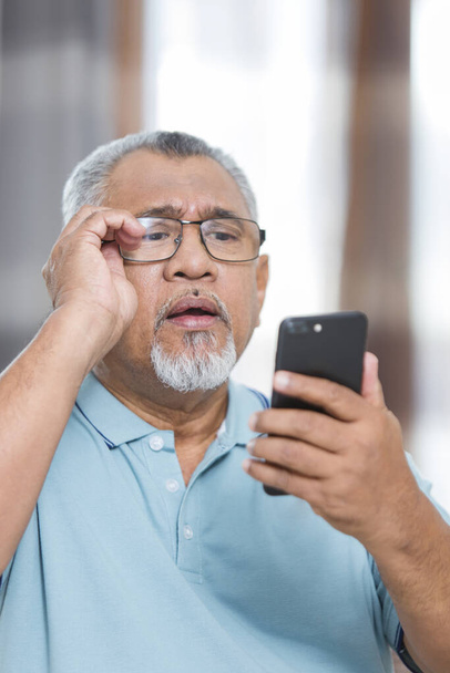 Senior man looking at his phone - Photo, Image