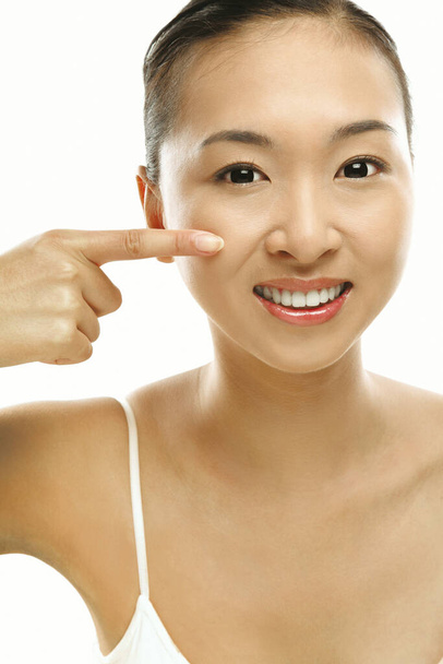 Woman pointing at her cheek with her finger - Foto, imagen
