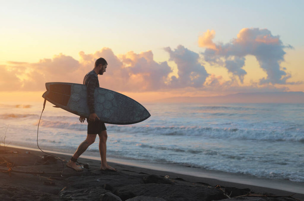 Surfing. Surfer With Surfboard On Sandy Beach. Beautiful Sunrise In Bali. Man Going To Surf In Ocean On Attractive Sky Background. - Foto, Imagen