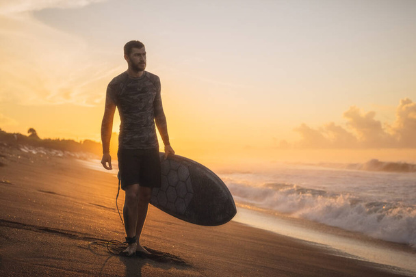 Surfing. Surfer Carrying Surfboard On Ocean Beach. Man Silhouette At Beautiful Sunrise In Bali. - Фото, зображення
