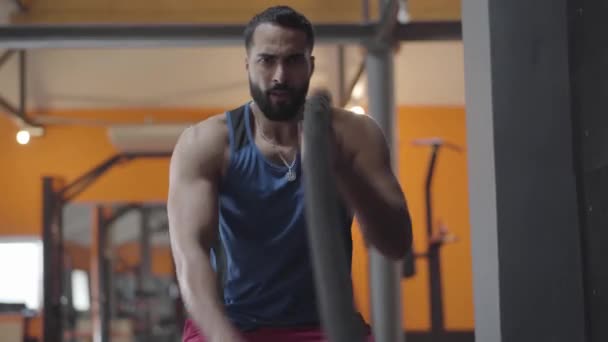 Front view of young serious sportsman ending crossfit exercise. Middle Eastern bearded man training in gym. Sport, health, lifestyle, tense. - Materiaali, video