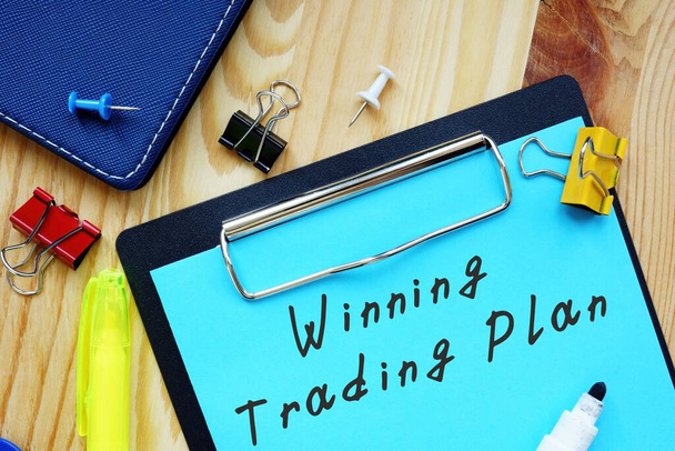 Het bijschrift op de foto is Winning Trading Plan. Notitieboekje, tafel, pennen. - Foto, afbeelding