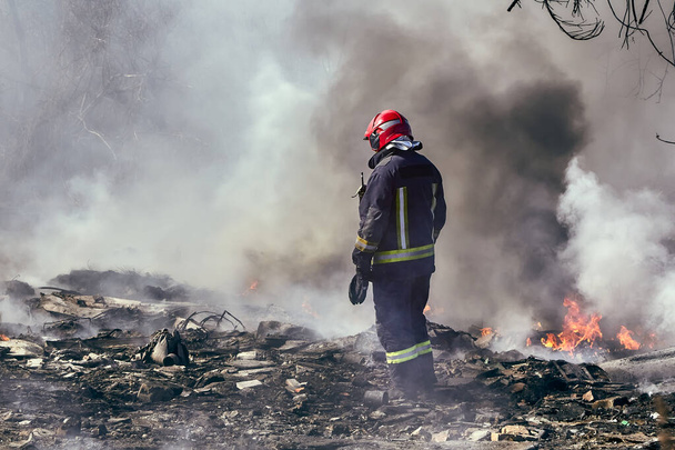 30. března 2020, Riga, Lotyšsko: hasič při hašení požáru na nelegálním skládce - Fotografie, Obrázek